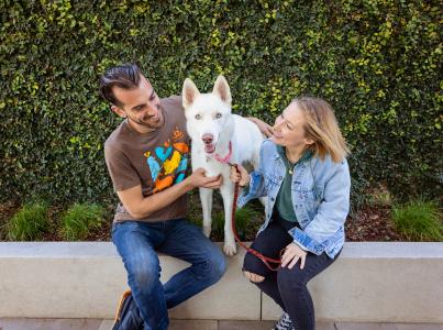 Two smiling people sitting outside with a dog in Los Angeles